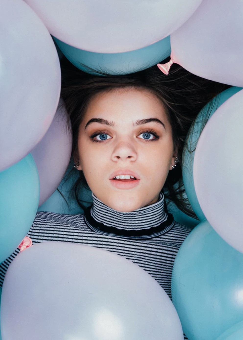 Headshot of person surrounded by pink and blue balloons.