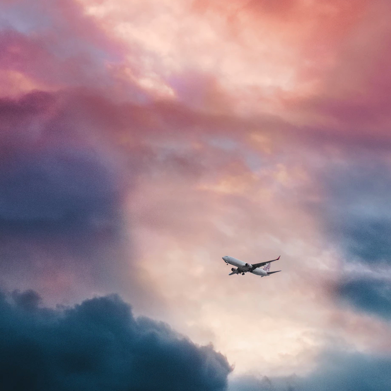 Airplane flying over pink and purple-coloured clouds